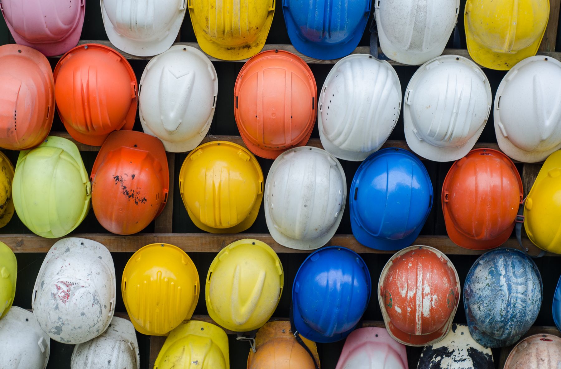 Rows of colourful safety helmets on a wall